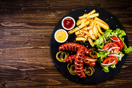 Grilled sausages, French fries and vegetables