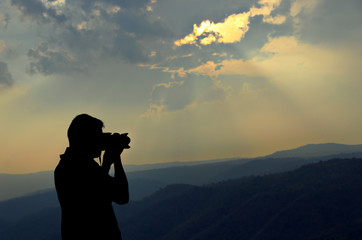 The photographer silhouette with mountain background.