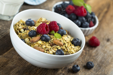 Homemade granola with fresh berries and mint, served with milk