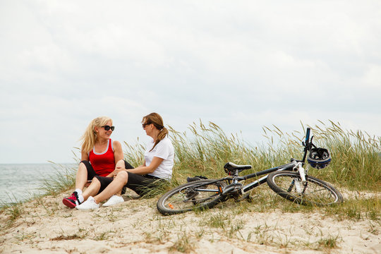 Women Resting After Riding Bike On The Beach