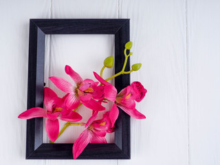 black wooden frame on white background with flowers, copy space for greetings