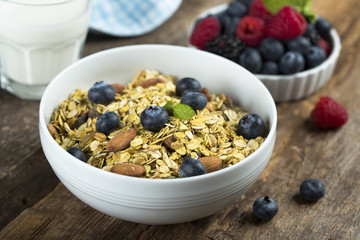 Homemade granola with fresh berries and mint, served with milk