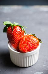 Ripe strawberries in small bowl on the rustic background. Selective focus.