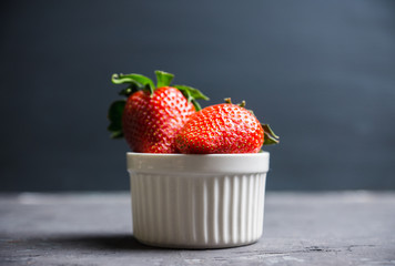 Ripe strawberries in small bowl on the rustic background. Selective focus.