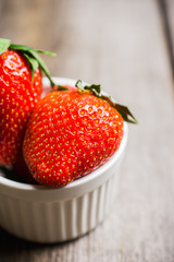 Ripe strawberries in small bowl on the rustic background. Selective focus.