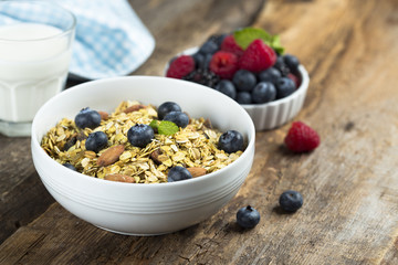 Homemade granola with fresh berries and mint, served with milk