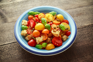Homemade Panzanella, Tomato traditional Italian salad with red, yellow, orange cherry tomatoes, capers, basil and ciabatta croutons. summer healthy food.