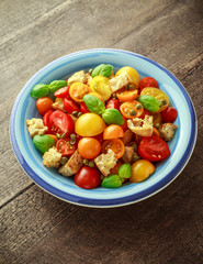 Homemade Panzanella, Tomato traditional Italian salad with red, yellow, orange cherry tomatoes, capers, basil and ciabatta croutons. summer healthy food.