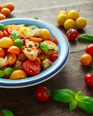 Obraz na płótnie Canvas Homemade Panzanella, Tomato traditional Italian salad with red, yellow, orange cherry tomatoes, capers, basil and ciabatta croutons. summer healthy food.