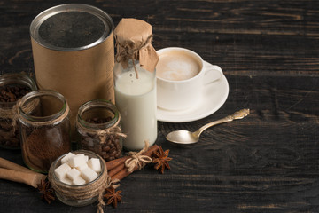 Grinded coffee, coffee beans, sugar, milk on a dark background with space for writing