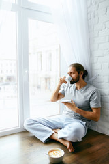 Morning Coffee. Man Enjoying Hot Drink Near Window