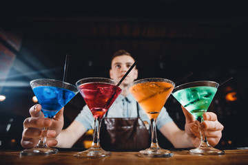 Barman mixes cocktail show with colorful alcoholic cocktails at bar counter.