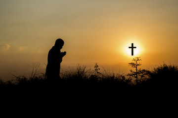 Fototapeta na wymiar Silhouette man praying in front of cross with faith and belief