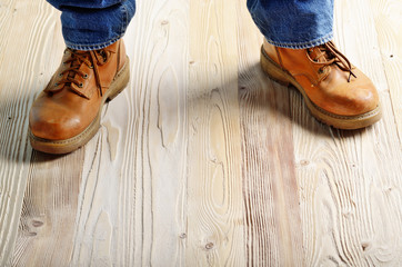 Carpenter feet in work boots standing on wooden floor. Place for text