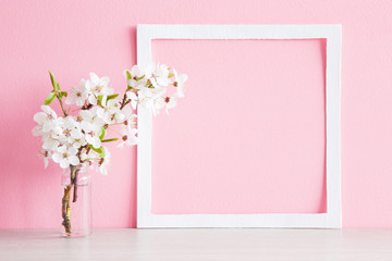 Fresh branches of cherry white blossoms in vase on table. Mockup for special offers as advertising or other ideas. Empty place for inspirational, motivational text or quote at soft pastel pink wall.