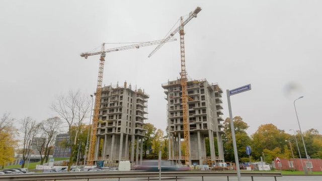 Timelapse of two skyscrapers being constructed by pillar crane in moody fog