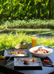 Various different dishes on dark background. Fish, steak, salad
