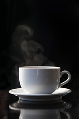 Steaming coffee or tea cup on dark background