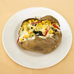 Baked kumpir potato stuffed with cheese, sausage, olives, peppers and corn