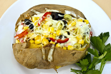 Baked kumpir potato stuffed with cheese, sausage, olives, peppers and corn
