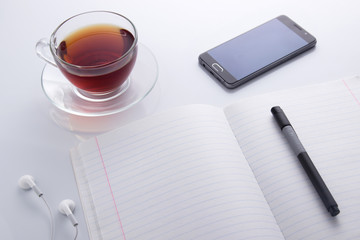 Open notebook on the table with tea, for writing.