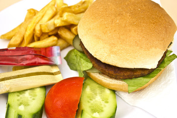 Hamburger with French fries, sliced cucumbers and tomatoes
