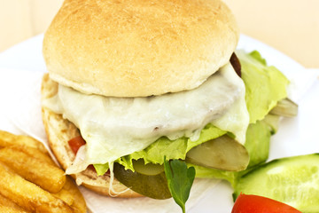 Cheeseburger with French fries, sliced cucumbers and tomatoes