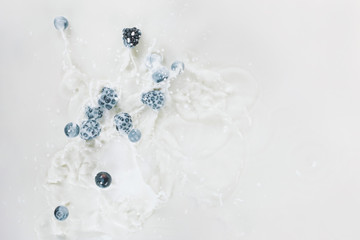 Splashes of milk with raw berries on white background