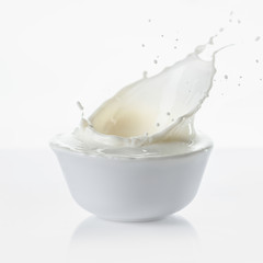 Milk splashing in white bowl on white background