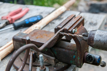 Piece of metal on the vise, hand operated drill press , focus on the iron chip.