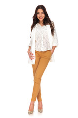 beautiful businesswoman standing with legs crossed and hand in pocket