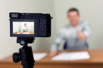 Young male blogger recording video at home using a tripod mounted digital camera