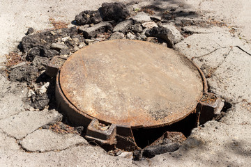 broken metal sewer hatch in the middle of an asphalt road