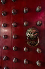 Traditional Chinese doors with brass lion head door knockers and ornamental studs. The number of studs represent status of the owner.