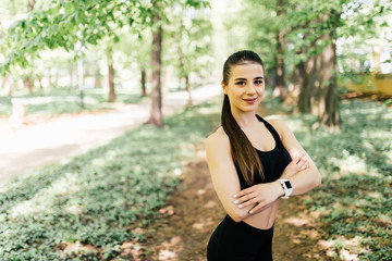 Portrait of smiling fit woman with hands folded standing at park
