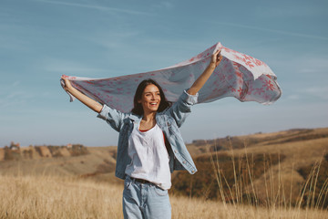 Young woman holding a scarf in the wind on a mountain