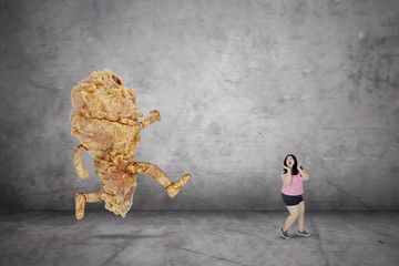Obese woman looks fearfully with a fried chicken