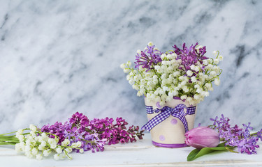Lily of the Valley,Lilac and Tulips  Bouquet in  Vase with Ribbon on a Marble  Background .Spring Flowers Background