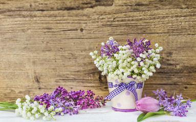 Lily of the Valley,Lilac and Tulips  Bouquet in  Vase with Ribbon on a Wooden Background .Spring Flowers Background