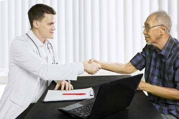 Elderly man shaking hands with his doctor