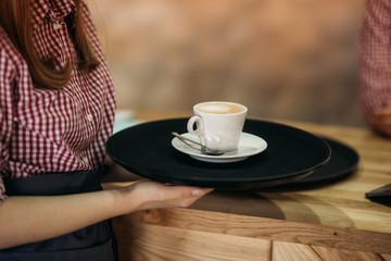 Waitress offering a cup of coffee in cafe