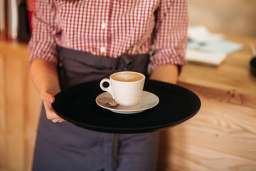 Waitress offering a cup of coffee in cafe