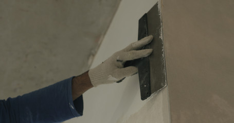 worker applying putty on the wall near corner
