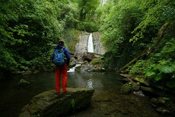 Tourist admires the waterfall in the forests of Sochi