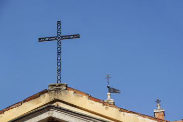 metal cross on a church roof with blue sky as a background
