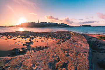 View from the tidal island of Grand Be to the city of Saint Malo and flooded path causeway at high tide at sunrise. Saint-Malo is famous city of Privateers is known as city corsaire, Brittany, France. - obrazy, fototapety, plakaty