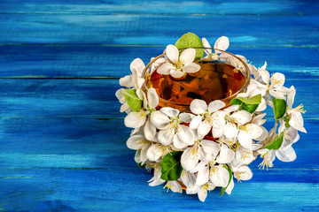 A cup of flower tea, decorated with apple blossoms lies on a blue wooden table. Concept of spring drink. Copy cpace for text.