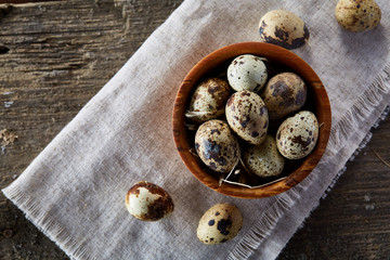 Bowl with eggs quail, eggs on a homespun napkin, boxwood on wooden background, close-up, selective focus