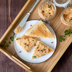 Fresh homemade chicken pate on toasted bread on tray over rustic background, top view