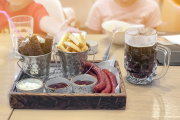 Fast food in cafe restaurant snack French fries, beer dark different types of sauces and mini sausages.